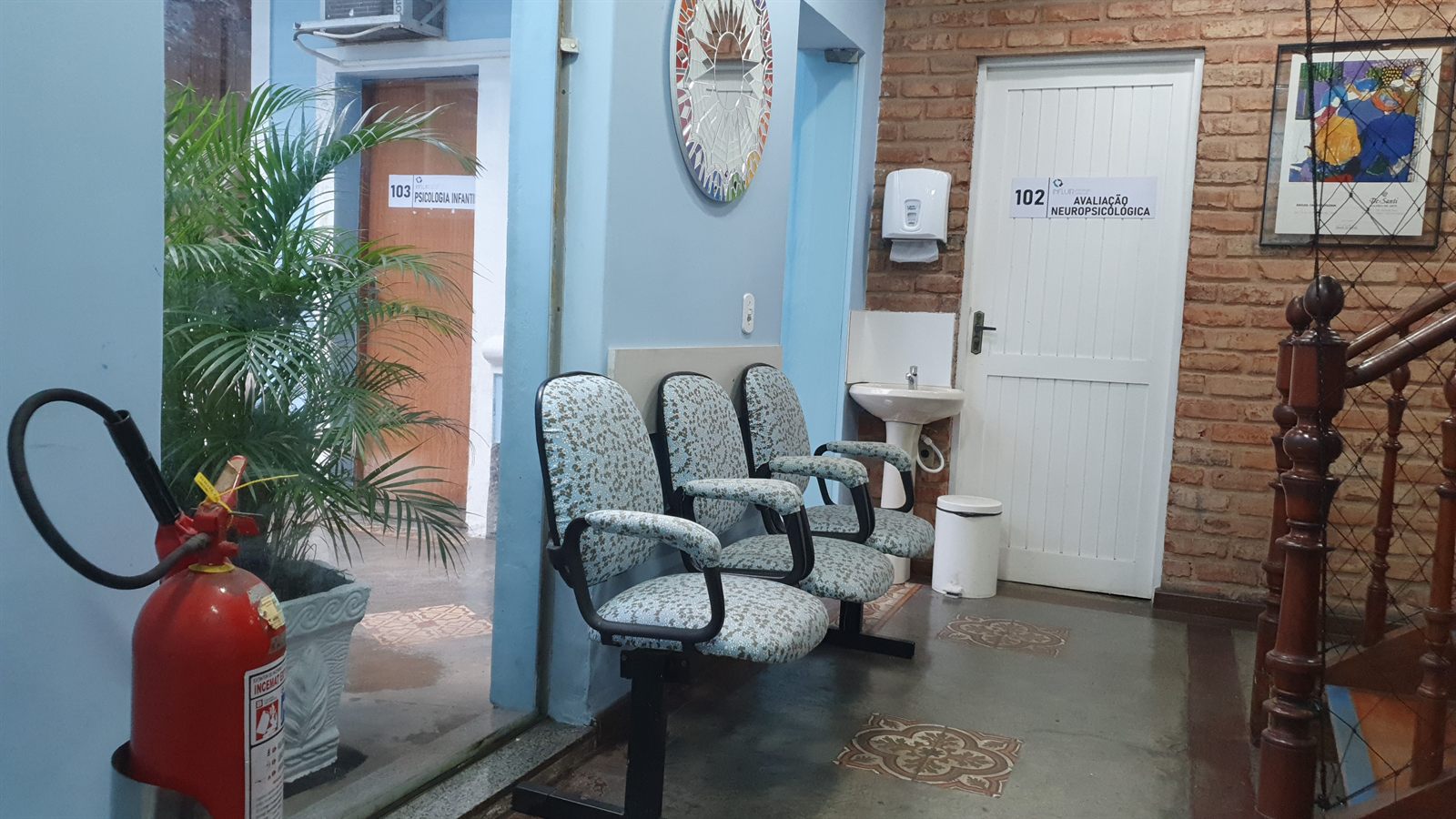 Recepção da Abraço TEA, com poltronas, plantas e as portas das salas de avaliação neuropsicológica e psicologia infantil
